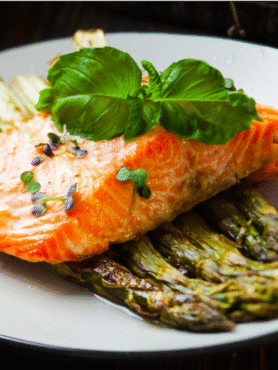 Salmon piled on top of asparagus on a white plate.
